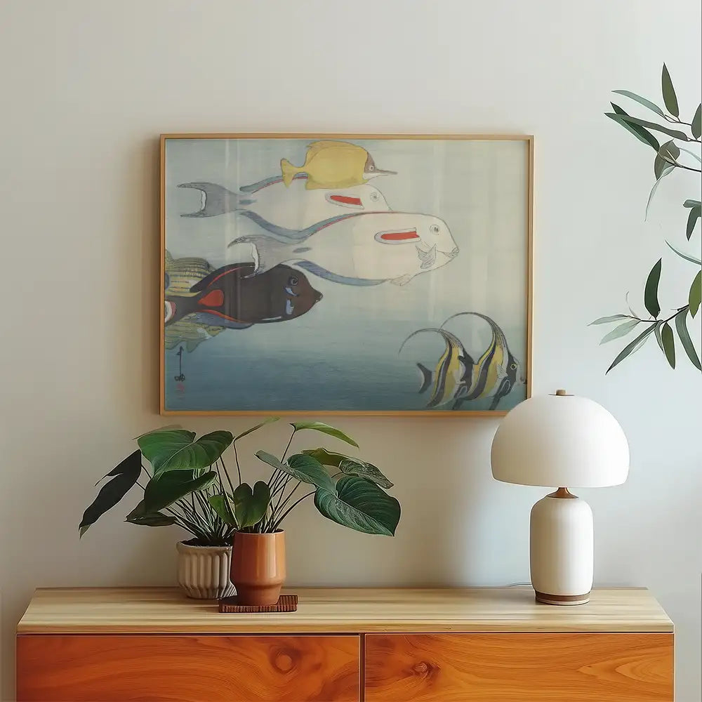 Painting of colorful fish swimming in a serene water setting, framed and displayed on a light wall above a wooden console table with decorative plants and a lamp.