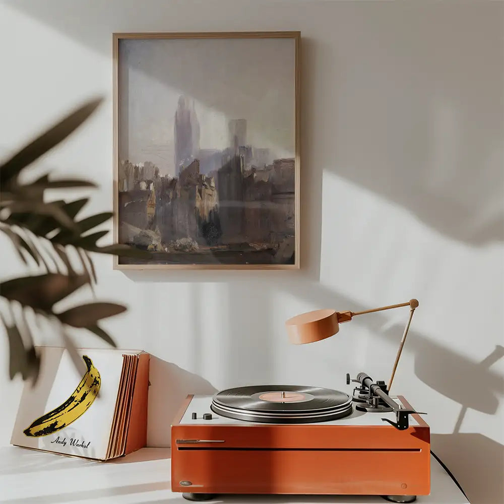 A cozy interior featuring a modern painting in a wooden frame hanging on the wall above a vintage record player with an orange finish, accompanied by a book of iconic album covers.