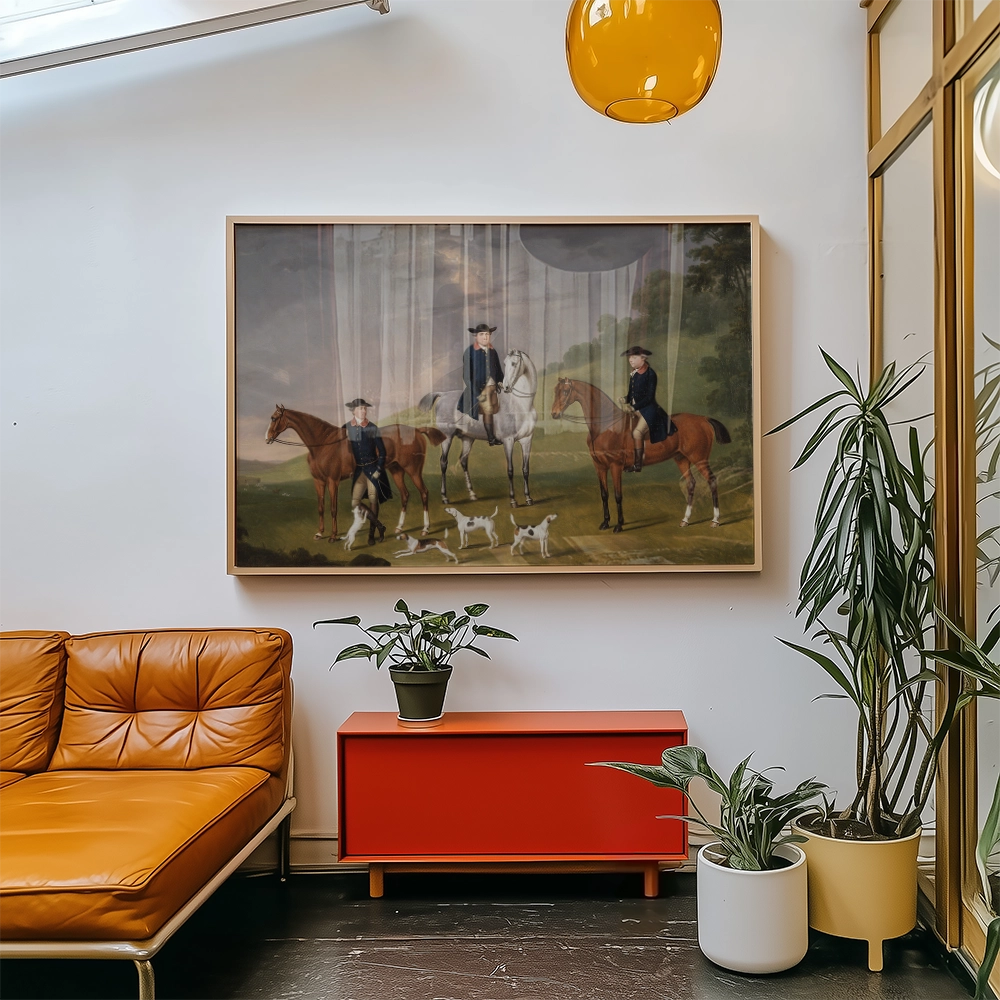 A framed painting of three riders on horses with dogs in a serene landscape, displayed in a modern living room setting with an orange couch and plants.