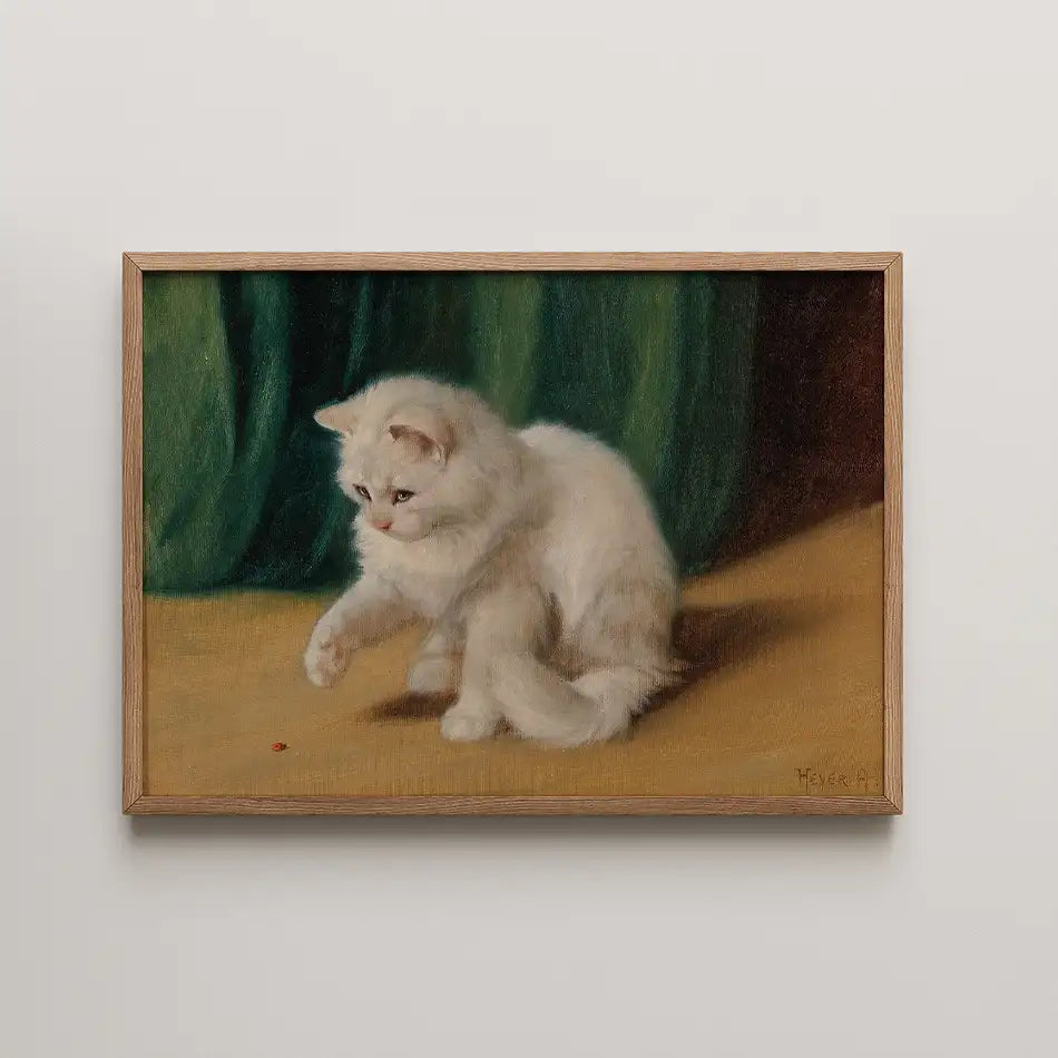 Painting of a playful white kitten reaching for a small object on a wooden floor, set against a green backdrop, framed in wood.