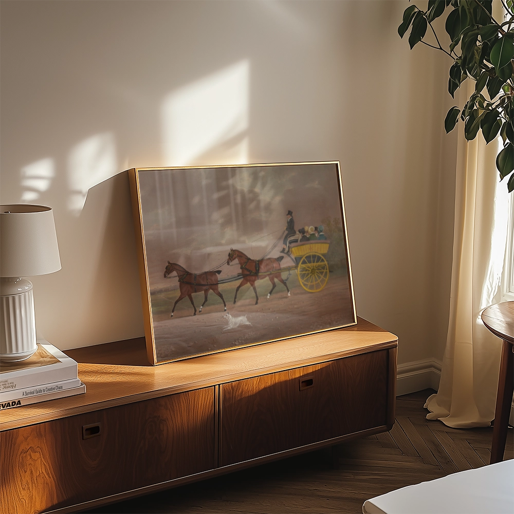 Framed painting of a horse-drawn carriage with two horses in a soft, natural setting, displayed on a wooden surface beside a lamp and indoor plant.