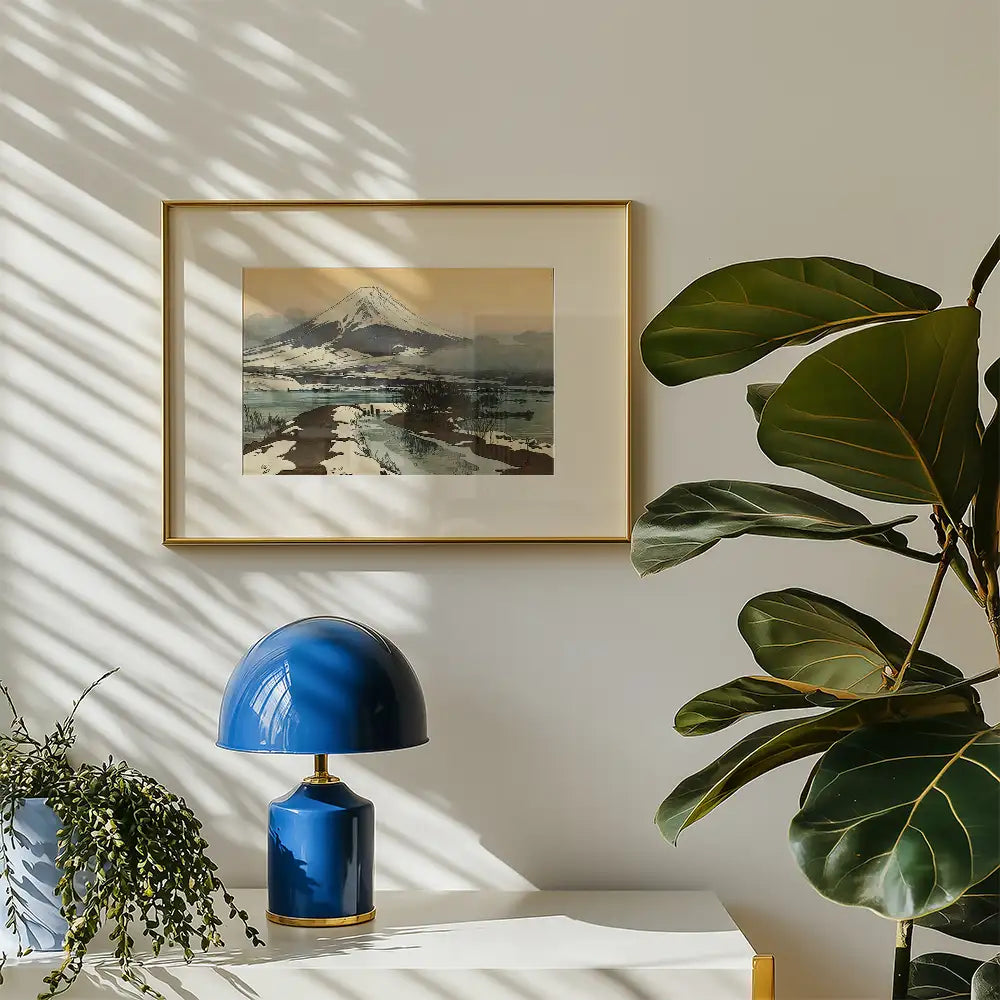 Framed painting of a snowy mountain landscape on a wall beside a blue lamp and a potted plant.
