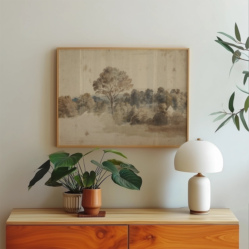 A framed watercolor painting of a serene landscape featuring trees and a soft color palette, displayed above a wooden console table with potted plants and a modern lamp.