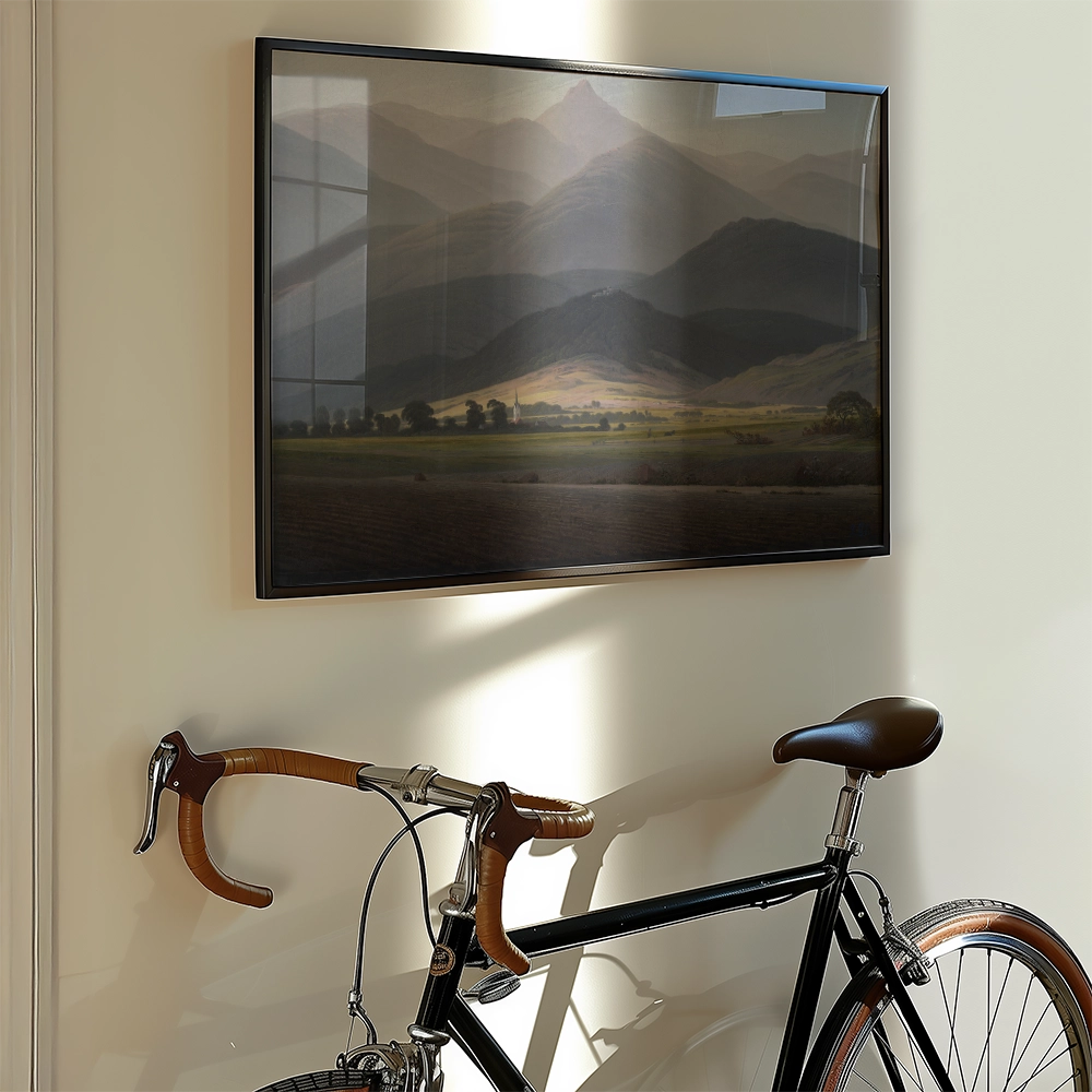 Landscape painting featuring mountains and a valley, framed and displayed on a wall next to a vintage bicycle.