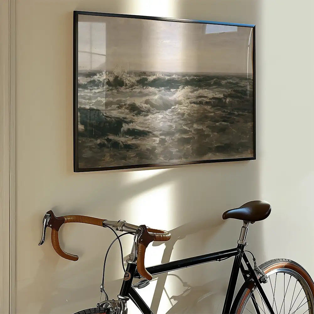 Painting of turbulent ocean waves framed and displayed on a wall next to a black bicycle.