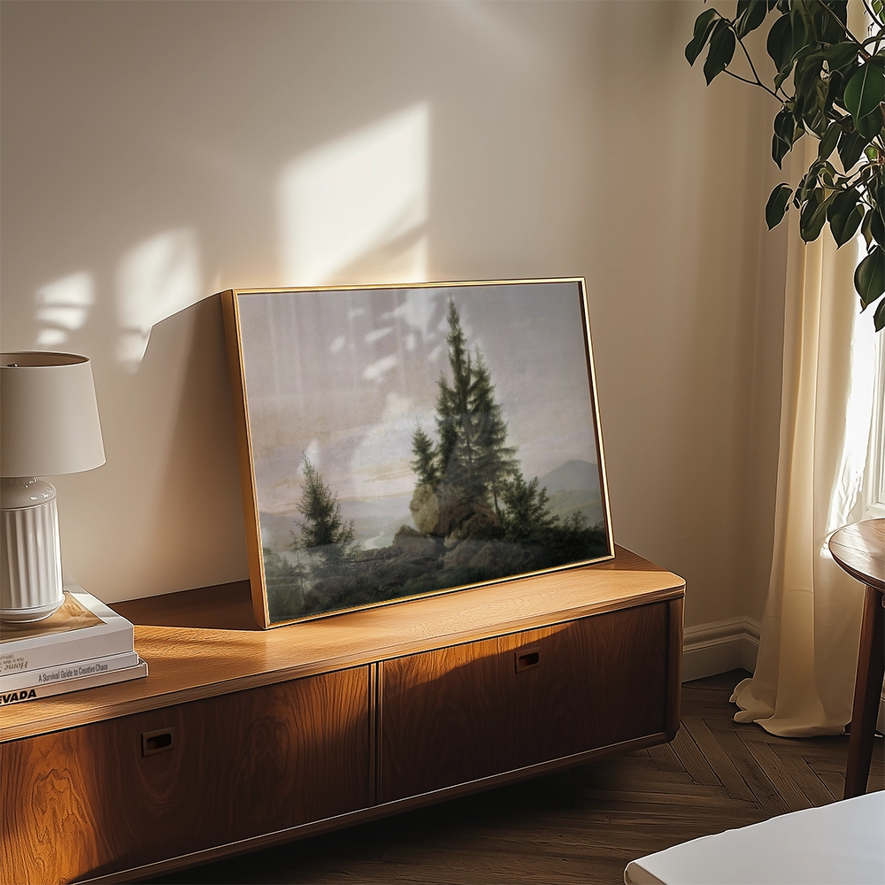 Framed landscape painting of pine trees on a wooden cabinet with a lamp and decorative items in a bright room.