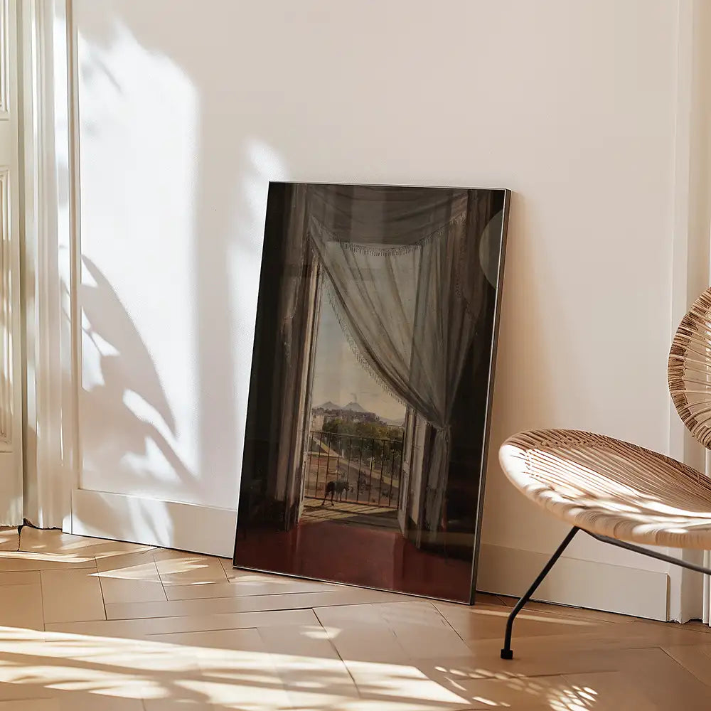 Framed painting depicting a scenic view with curtains, leaning against a wall next to a stylish chair in a bright interior space.