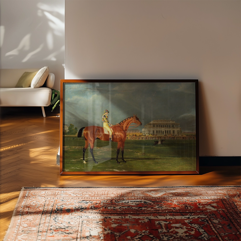 A framed painting of a horse and rider in a landscape setting, displayed on a wooden floor next to a plush sofa and a patterned rug.