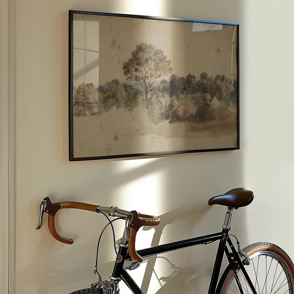 Framed watercolor painting of a serene landscape depicting trees and hills, hanging on a wall next to a vintage bicycle.