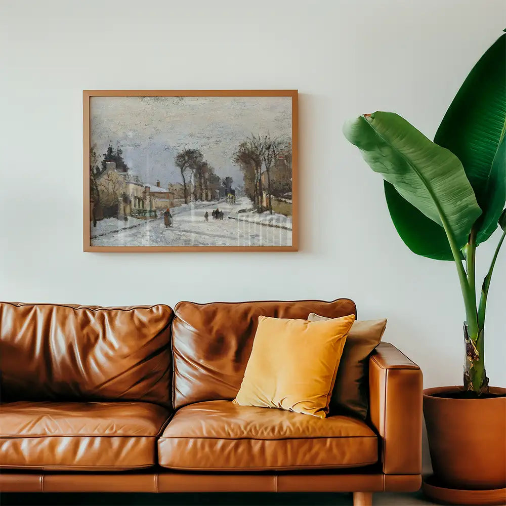 Interior scene featuring a framed winter landscape painting above a brown leather sofa with a yellow pillow, accompanied by a green plant in a pot.