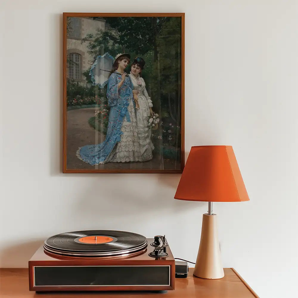 Painting of two women in elegant dresses standing in a garden, framed on a wall above a vintage record player and an orange table lamp.