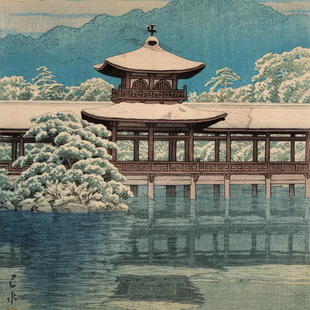 Snow-covered traditional Japanese building overlooking a serene body of water with mountains in the background.