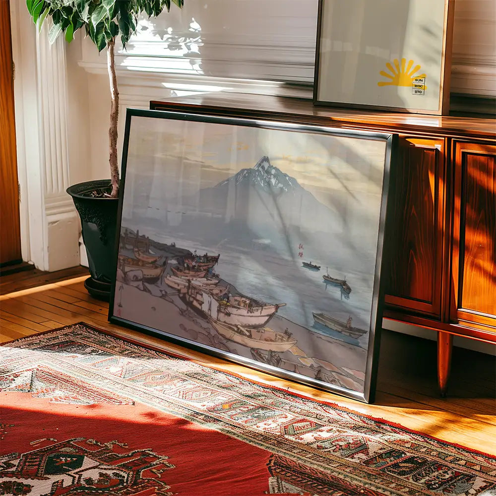 Framed painting of a serene coastal scene with boats and a mountain in the background, resting against a wooden cabinet on a patterned rug.