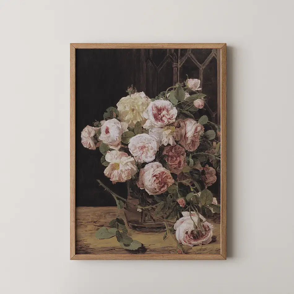 Vintage floral painting of a bouquet of roses in a glass vase, framed in natural wood, on a light wall.