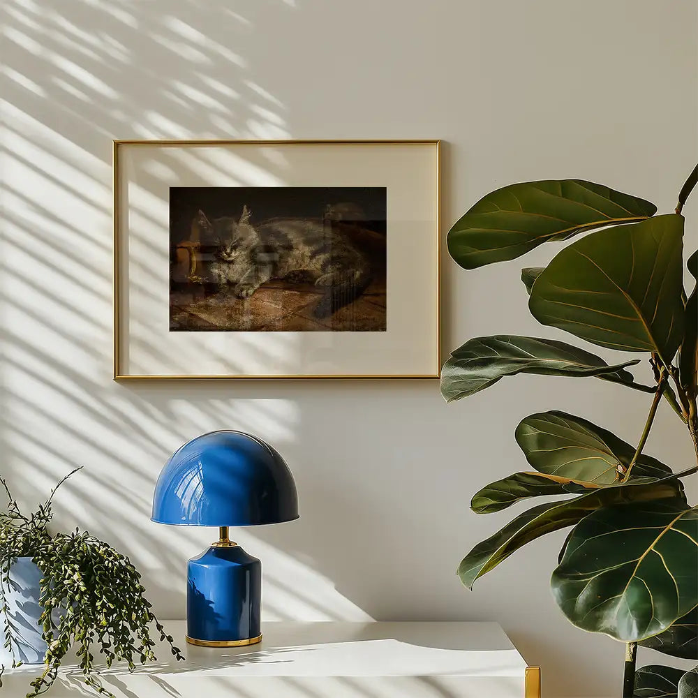 Painting of a cat framed in gold, displayed on a wall with natural light casting shadows, alongside a blue lamp and greenery.