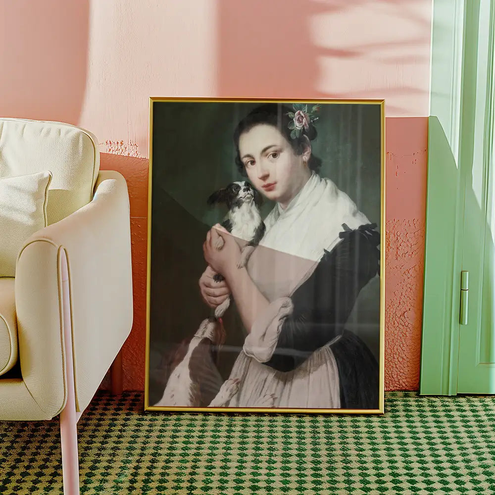 Portrait of a young woman holding a small dog, framed in gold, displayed in a cozy interior setting.