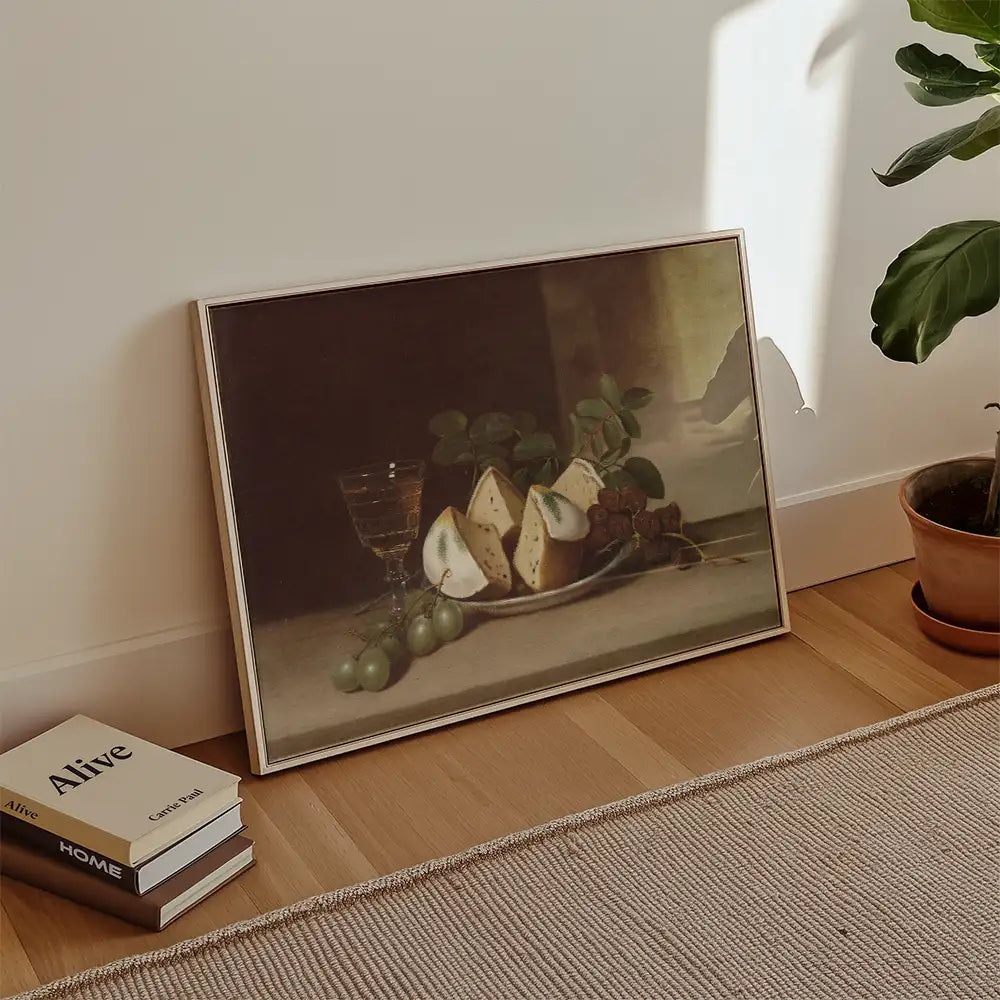 Still life painting featuring sliced cheese, grapes, and a glass on a plate, leaning against a wall in a modern interior setting.