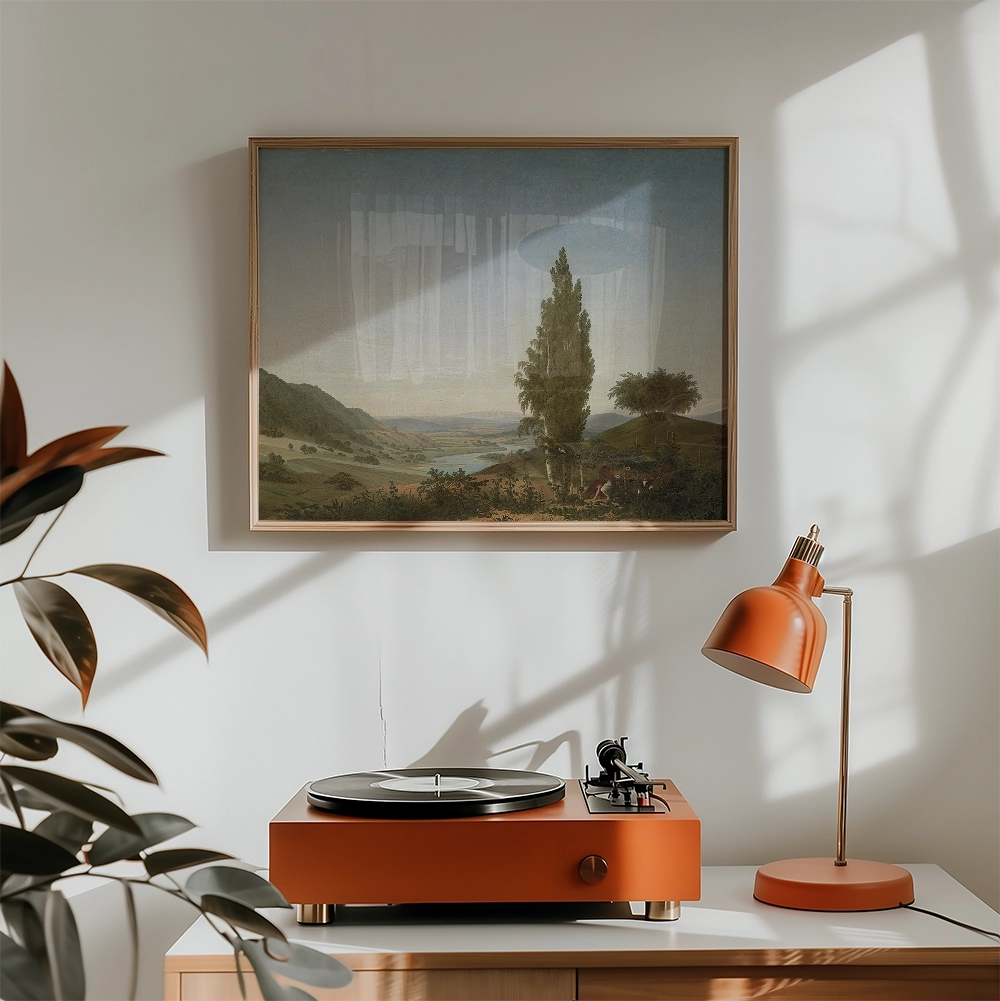 Painting of a serene landscape with mountains and trees, framed and hung on a wall above an orange record player and a matching lamp.