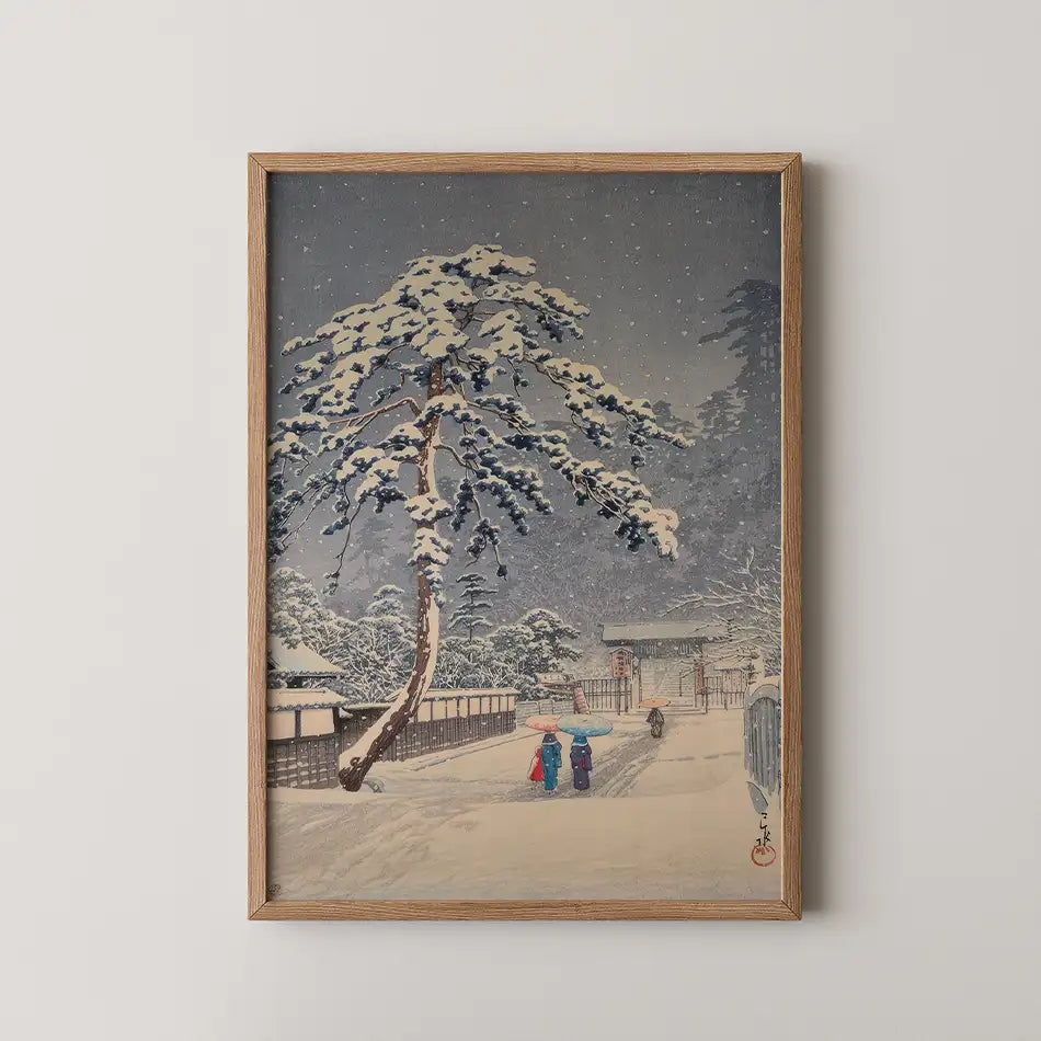 Framed painting of a snow-covered landscape featuring two figures with umbrellas walking along a path beside a traditional Japanese building and a tall pine tree.