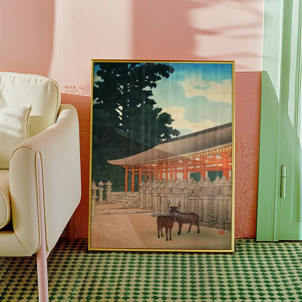 Painting of a traditional Japanese scene featuring deer in front of a historic building, framed and displayed against a pastel-colored wall.