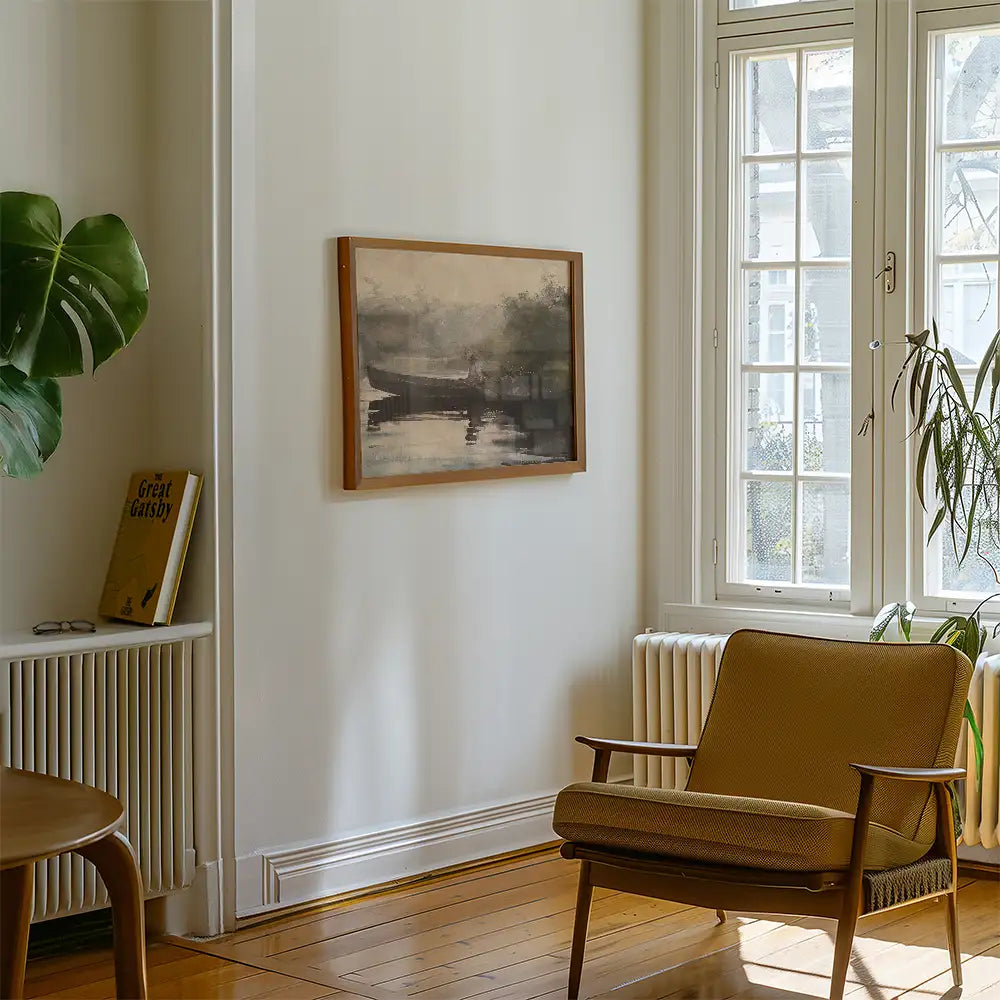 A framed painting of a serene landscape hanging on a white wall in a modern living room with a cozy chair and a potted plant.