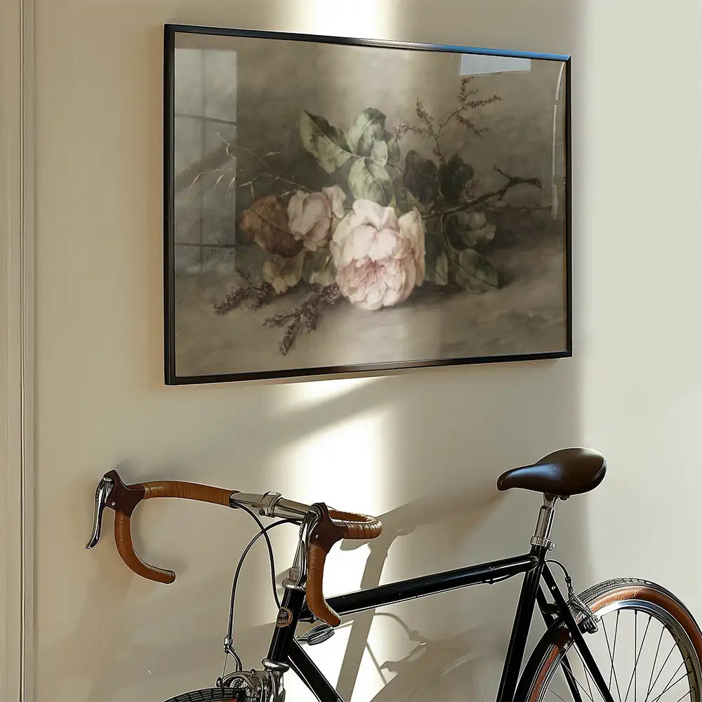 Framed painting of pink peonies and green leaves hanging on a wall beside a black bicycle with brown accents.