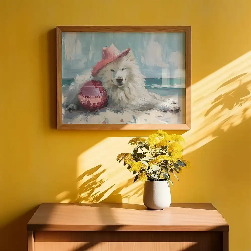 Modern art print featuring a playful Samoyed dog lounging on the beach with a pink hat and disco ball, framed in wood against a bright yellow wall.