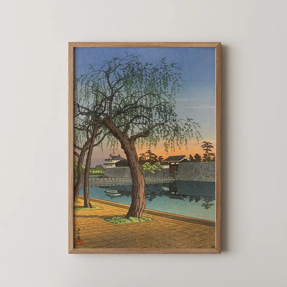 Framed painting of a tranquil lakeside scene featuring a weeping willow tree, traditional buildings, and a sunset reflection on the water.