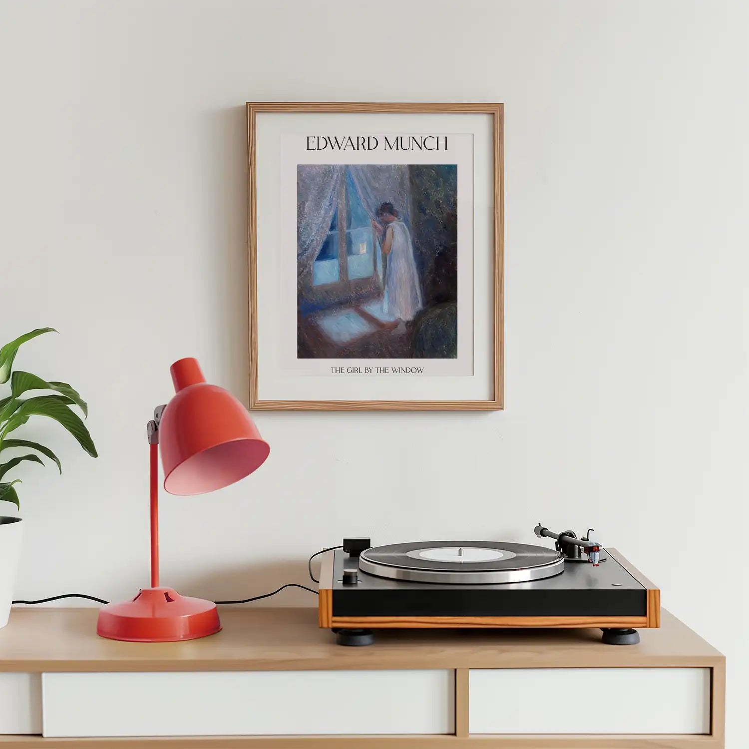 Framed poster of Edward Munch's "The Girl by the Window" displayed above a record player and a red desk lamp in a modern interior setting.