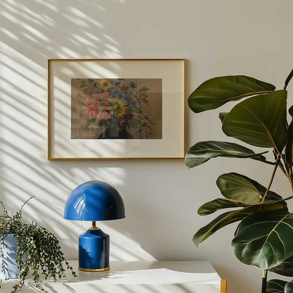Framed floral painting on a wall next to a blue table lamp and a green potted plant.