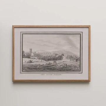 Framed print of "The South Parade," depicting a scenic landscape with a river, cows, and distant hills in a monochromatic style.