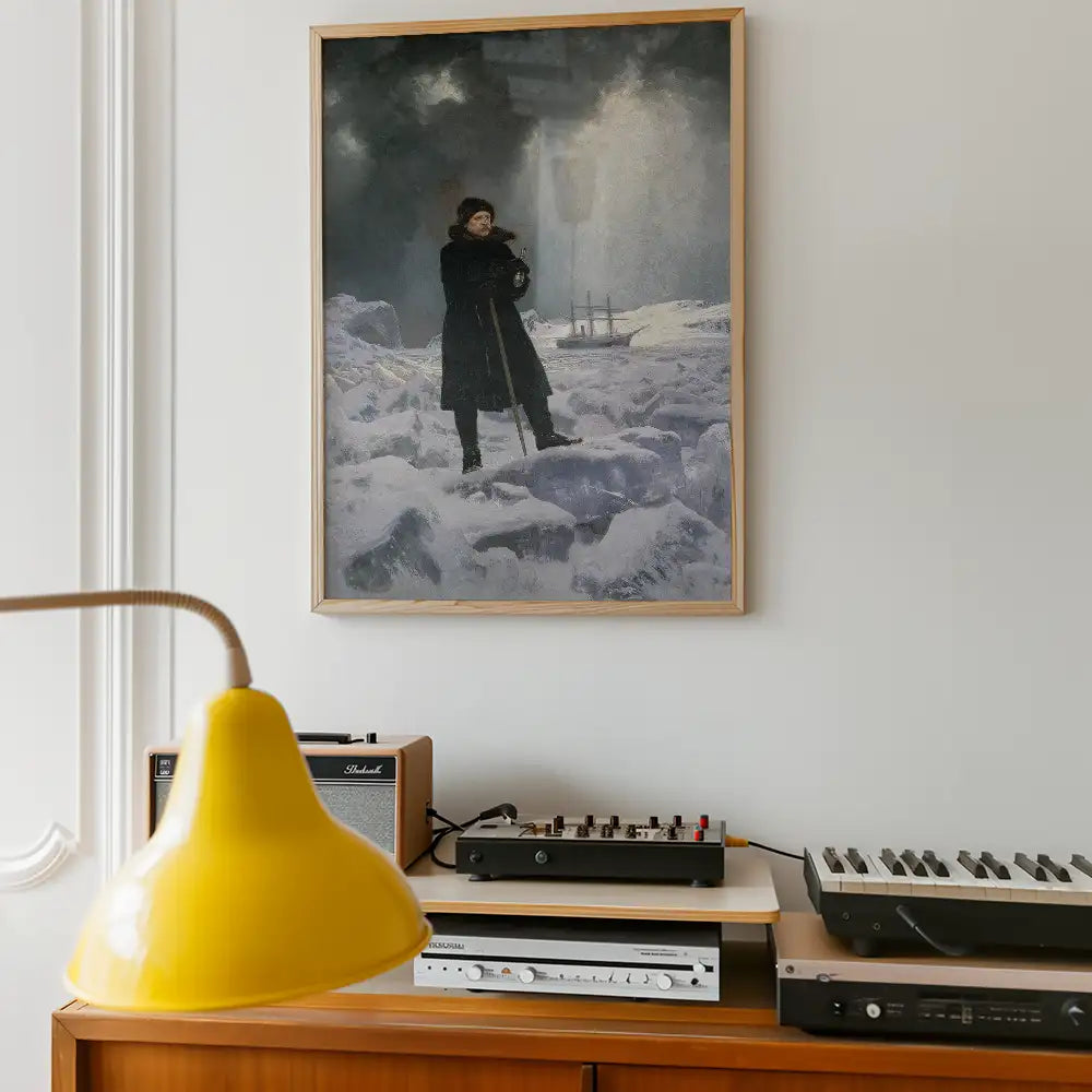 Framed painting of a person standing on icy terrain with a ship in the background, displayed on a wall above a wooden console with a yellow lamp and audio equipment.