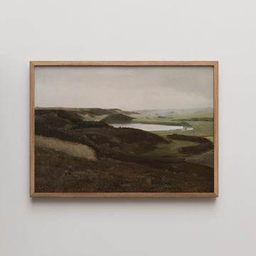 Framed landscape painting of rolling hills and a serene lake under a cloudy sky