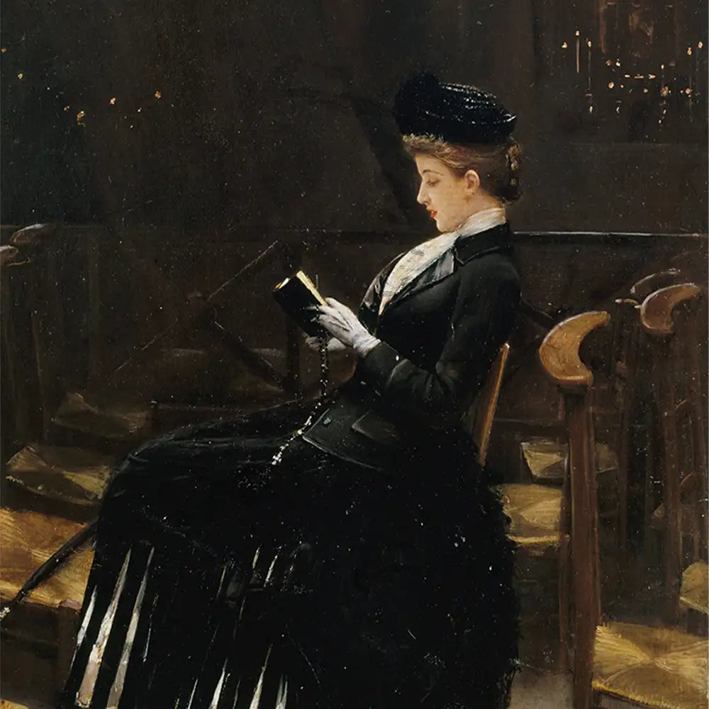 A woman in a black dress and hat sitting on a chair, reading a book in a dimly lit room.