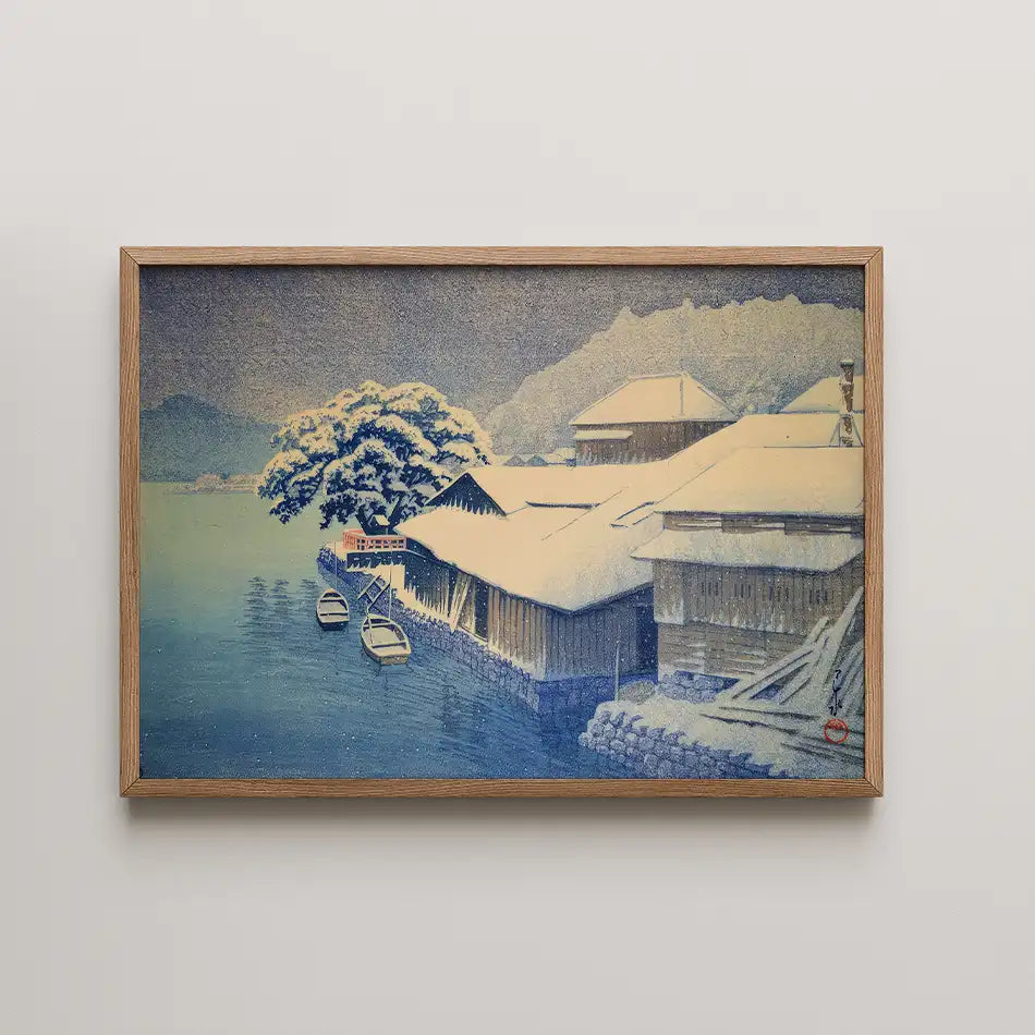 Framed painting of a serene winter scene with snow-covered buildings and boats by a calm body of water.