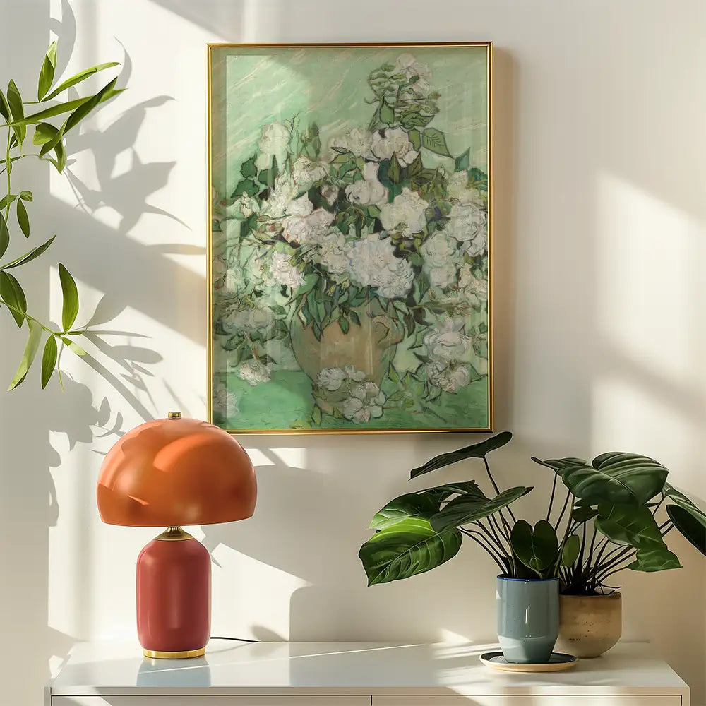 Floral painting in a gold frame displayed on a wall alongside a modern lamp and potted plants.