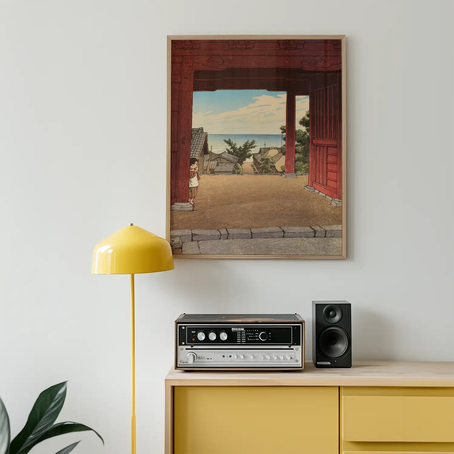 A framed painting depicting a serene landscape with a child standing in a doorway, accompanied by a yellow floor lamp and vintage stereo on a wooden cabinet.