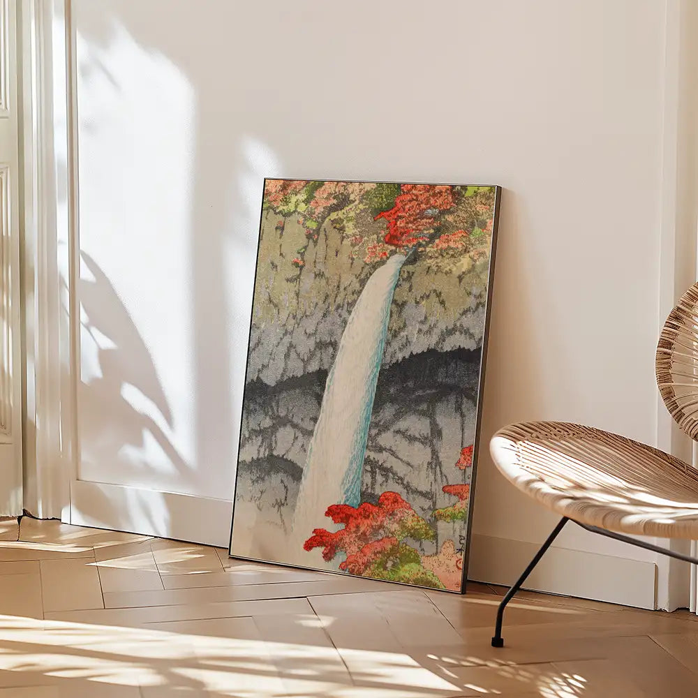 Painting of a waterfall surrounded by colorful trees, leaning against a wall in a modern interior setting.