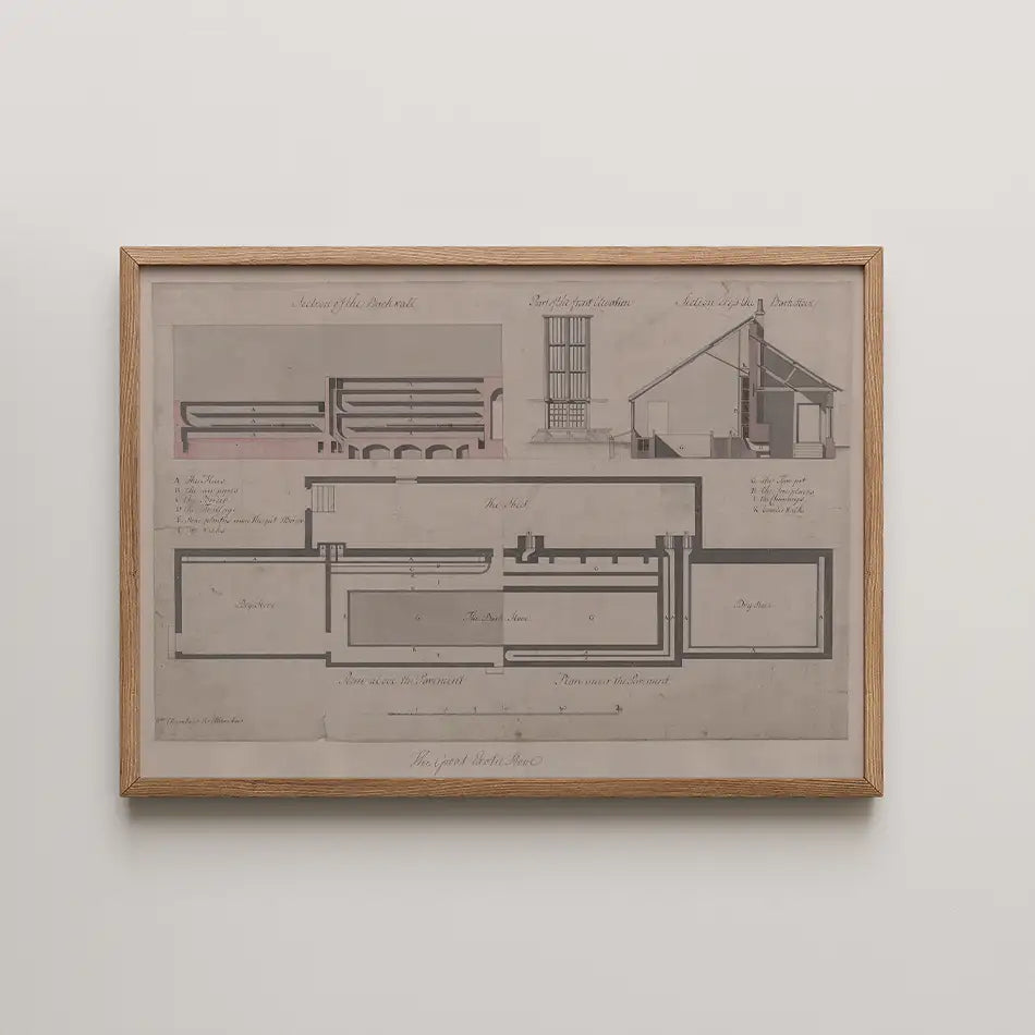 Architectural blueprint artwork framed in wood, featuring detailed drawings of building layouts and sections in muted tones.