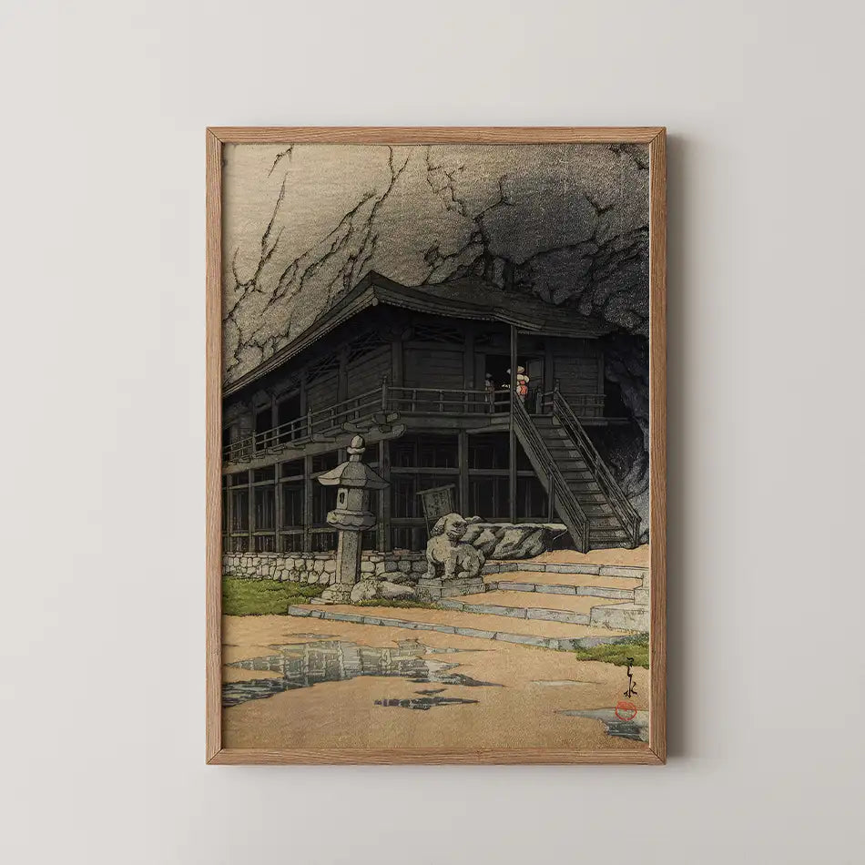 Framed painting of a traditional Japanese house with stone lanterns and figures, set against a textured backdrop.
