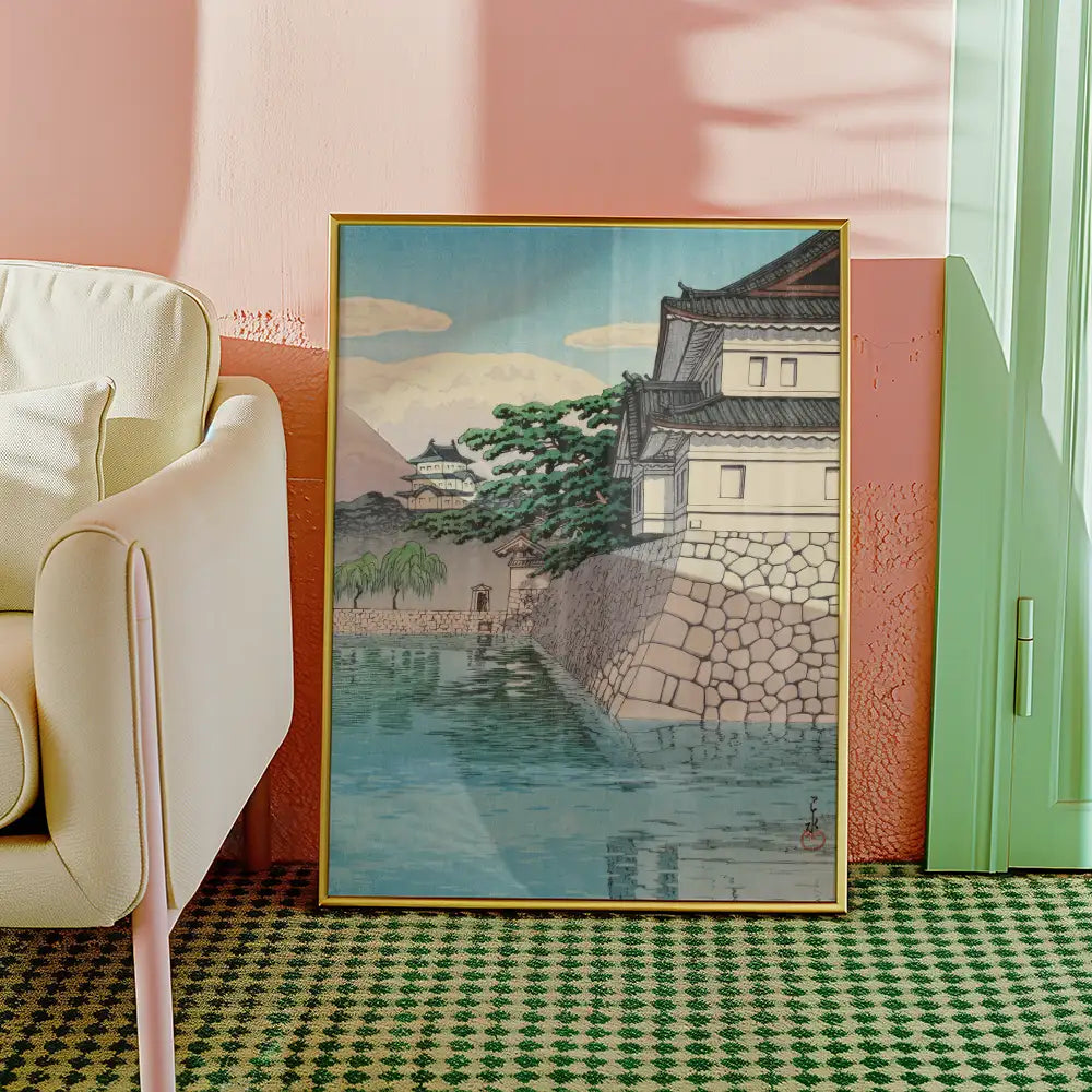 Framed painting of a tranquil landscape featuring a Japanese-style building by a body of water, set against mountains and trees, displayed in a modern interior.