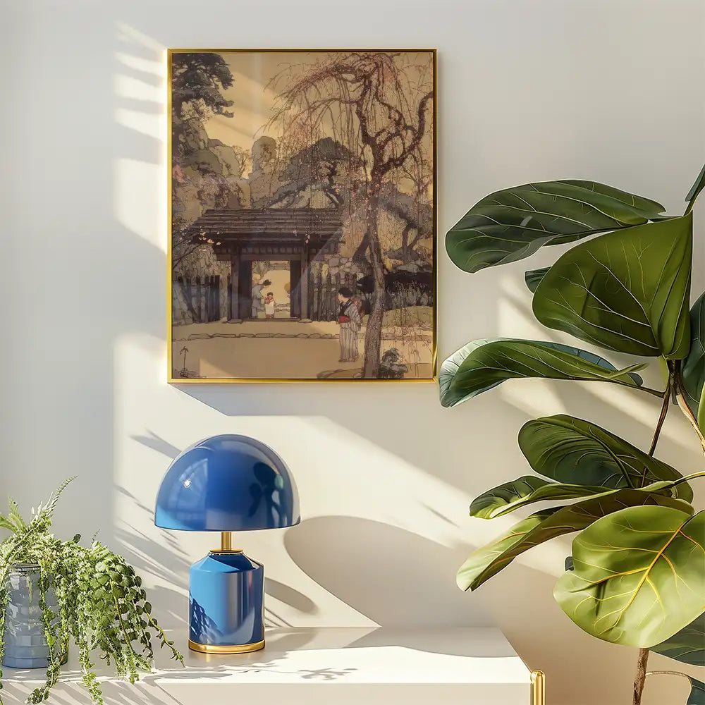 Framed painting of a serene landscape with a traditional gate, hung on a wall beside a blue lamp and a potted plant.