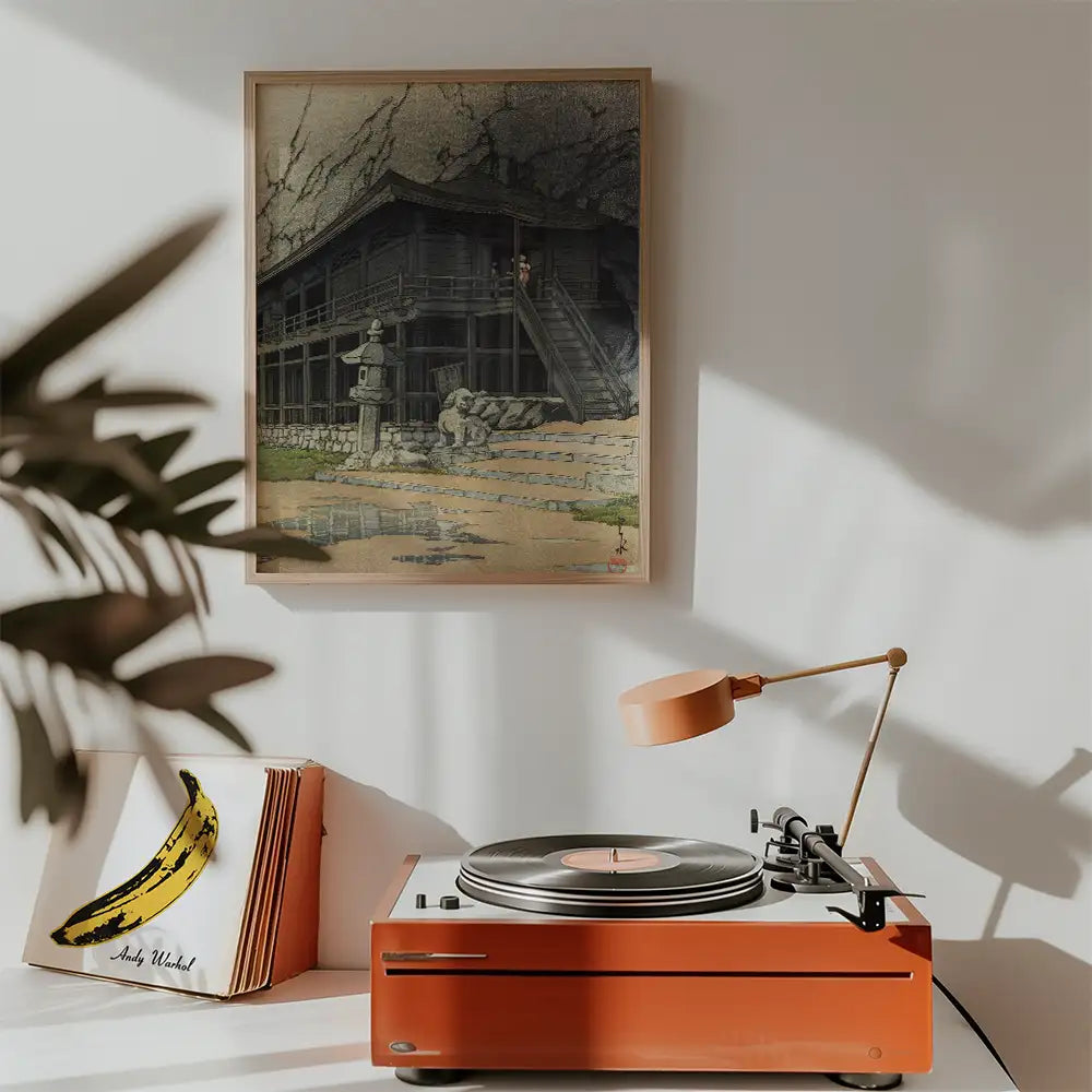 Painting of a traditional Japanese building displayed above a vintage record player in a modern interior setting.