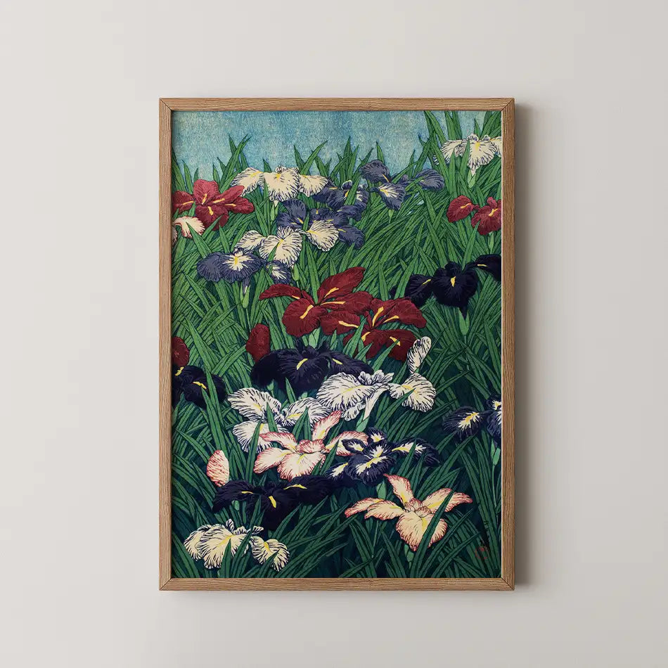 Framed painting of colorful irises in a lush green field with a blue sky backdrop.