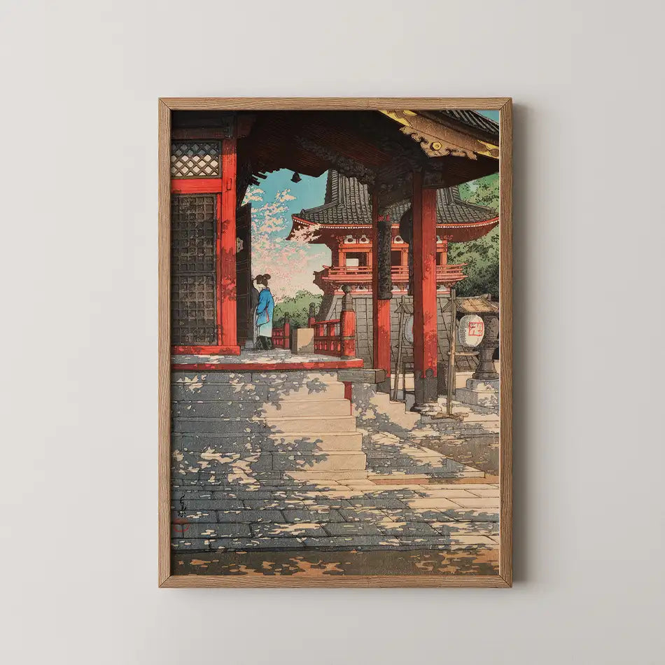 A traditional Japanese painting depicting a serene temple scene with a figure in blue, framed in natural wood.