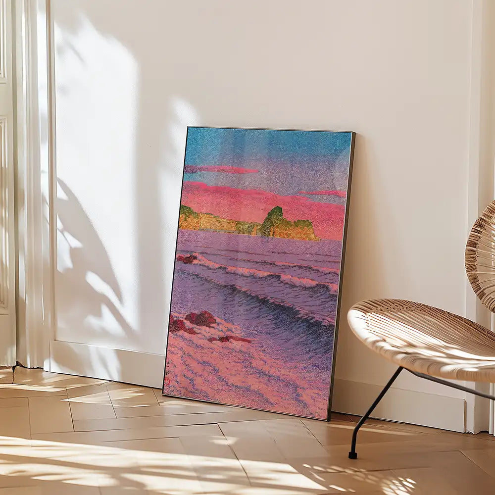 A colorful landscape painting featuring waves, cliffs, and a sunset, leaning against a wall next to a woven chair.