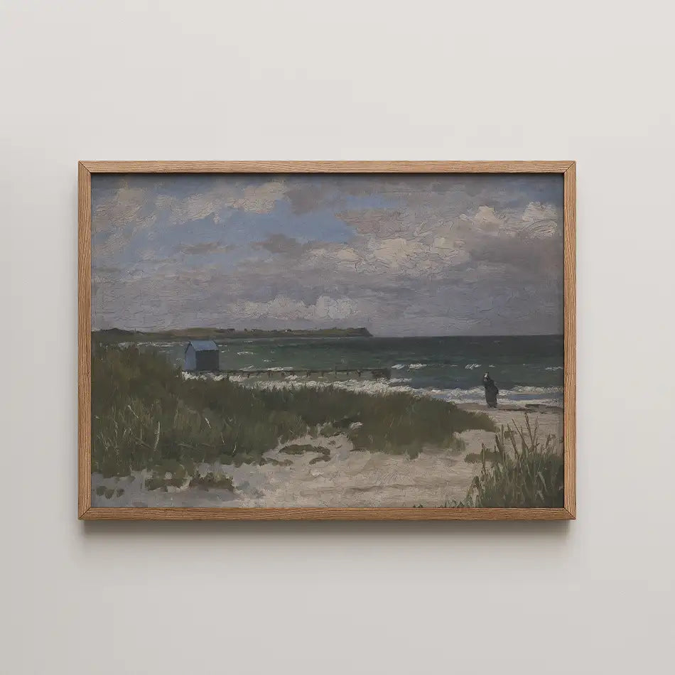 Framed painting of a beach scene with a figure standing near the shoreline, surrounded by grass and a cloudy sky.
