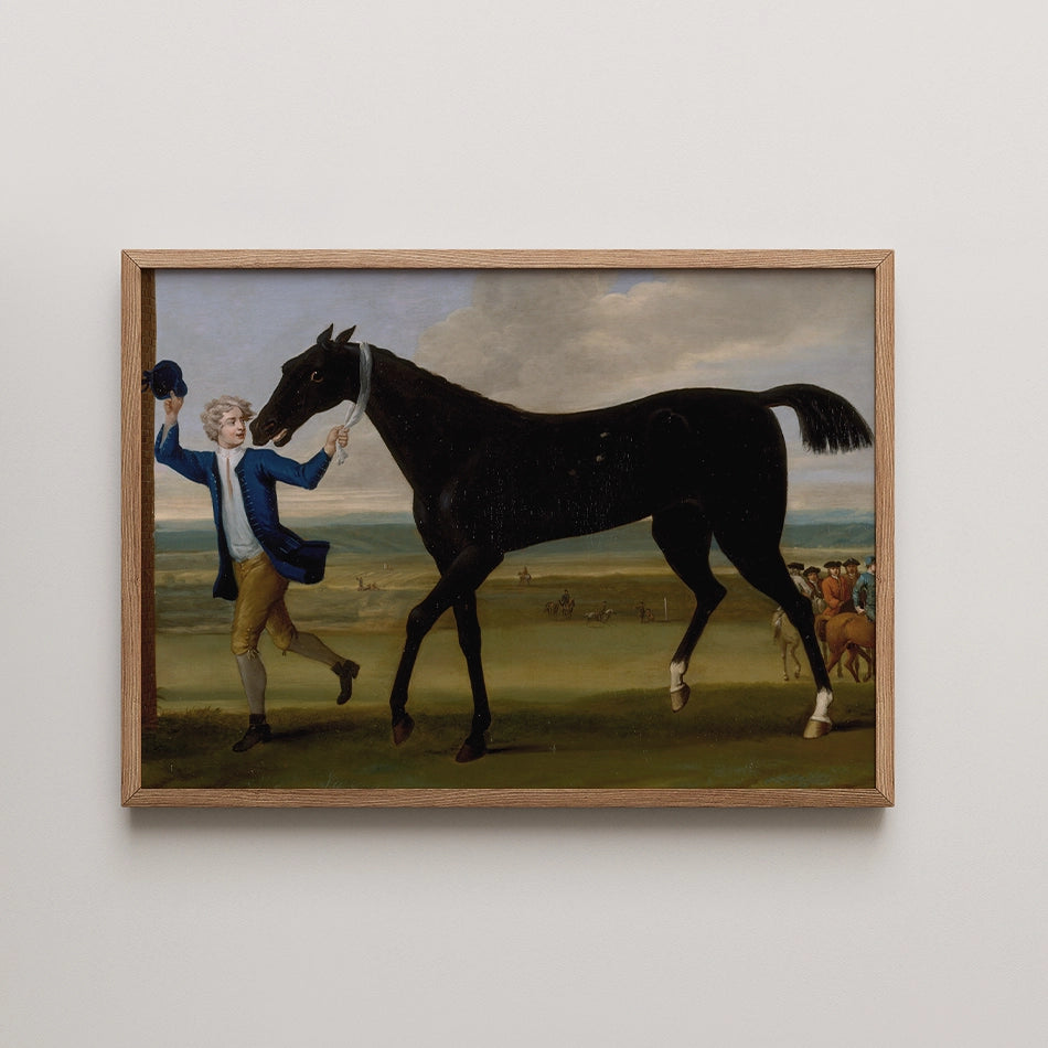 Painting of a man in a blue jacket leading a black horse in a landscape, framed in light wood.