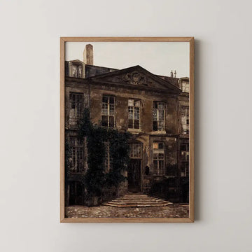 Framed painting of a historic building with ivy on the facade and a stone pathway, displayed on a light wall.