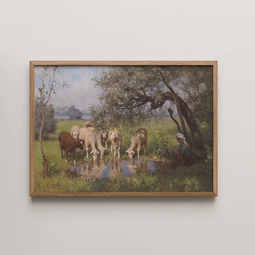 Framed painting of sheep grazing by a pond with a figure sitting under a tree in a lush green landscape.